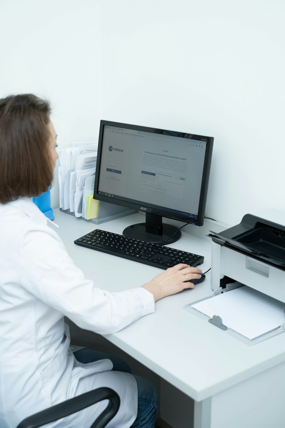 Servizi Professionista medico lavora al computer in un ufficio affollato.