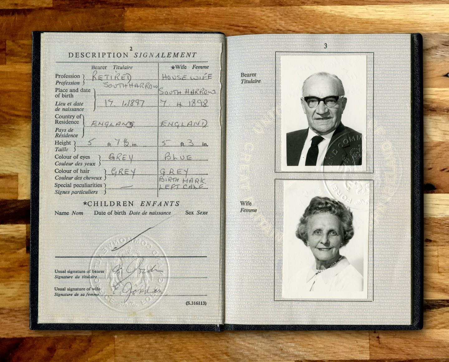 Servizi Un passaporto aperto con ritratti e timbri appoggiato sul legno.